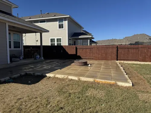 New paver patio with a built-in fire pit, edged in cut stone, in a fenced Georgetown back yard