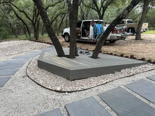 Composite deck wrapped around two live oaks, edged in steel and river rock