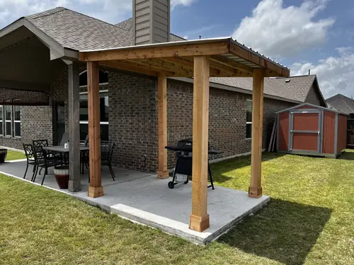 Cedar-post patio cover with a metal roof built over a poured concrete slab