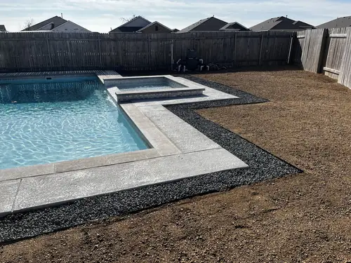 Pool and spa surround finished with broom-concrete decking and black gravel borders