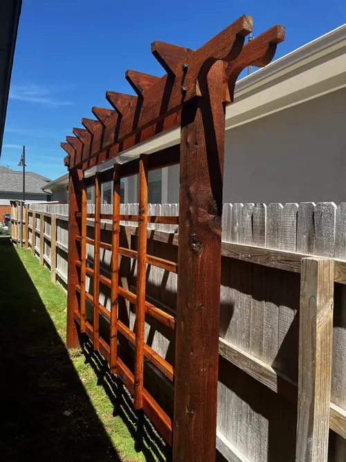 Stained cedar pergola and trellis screen built along a fence line