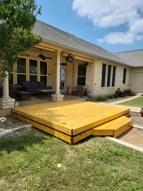 Pressure-treated wood deck with a step built off a covered stone porch