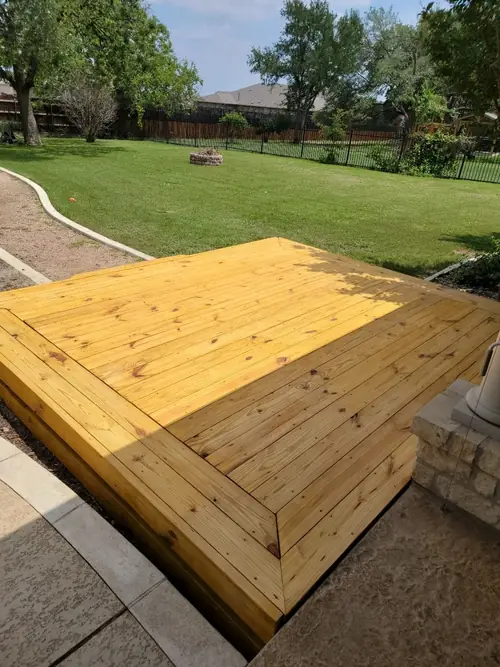 Pressure-treated deck platform built at the edge of a lawn