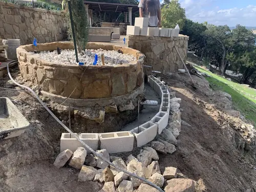 Stone planter and block retaining wall taking shape above a Hill Country lake view