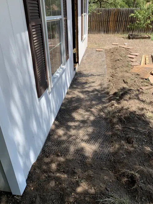 Hardware-cloth skirting laid along a foundation line ahead of backfill