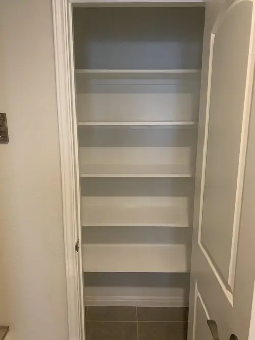 Built-in painted pantry shelving fitted wall to wall inside a closet